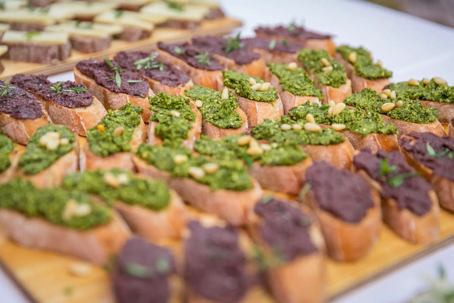 Crostini mit grünen und dunklen Gemüseaufstrichen auf einem Buffet angerichtet.